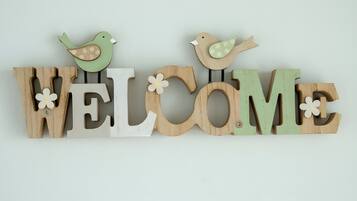 Ein Holzschild mit der Aufschrift 'WELCOME' und zwei darauf sitzenden Vögeln.