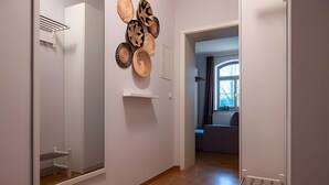 Een gang met een kast, een wandrek en een deur naar een andere kamer.