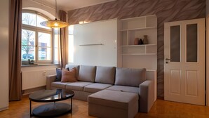 Een moderne woonkamer met een bank, een poef en een glazen deur.