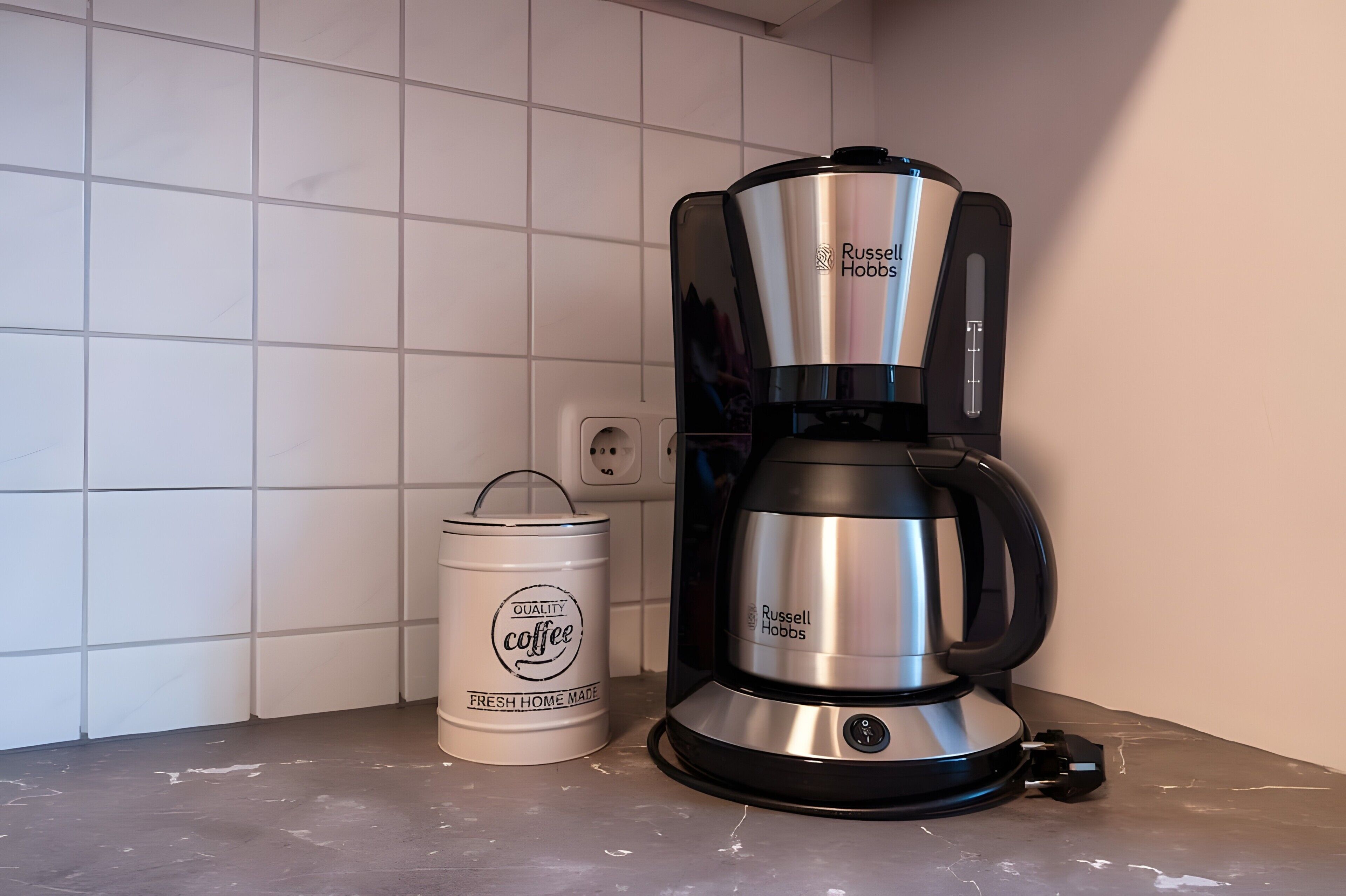A coffee maker and a canister on a kitchen counter.