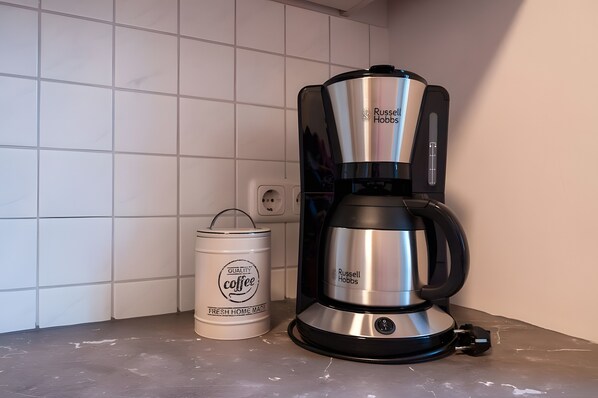 Una cafetera y un recipiente en la encimera de la cocina.