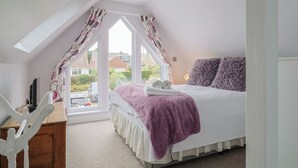 A bedroom with a bed, a desk, and a window with curtains. - Cherry Pip (Bridport)