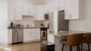 A modern kitchen with white cabinets, stainless steel appliances, and a wooden floor. - Designer Combo Loft 2E & 2W|Gold Coast/River North (Chicago)