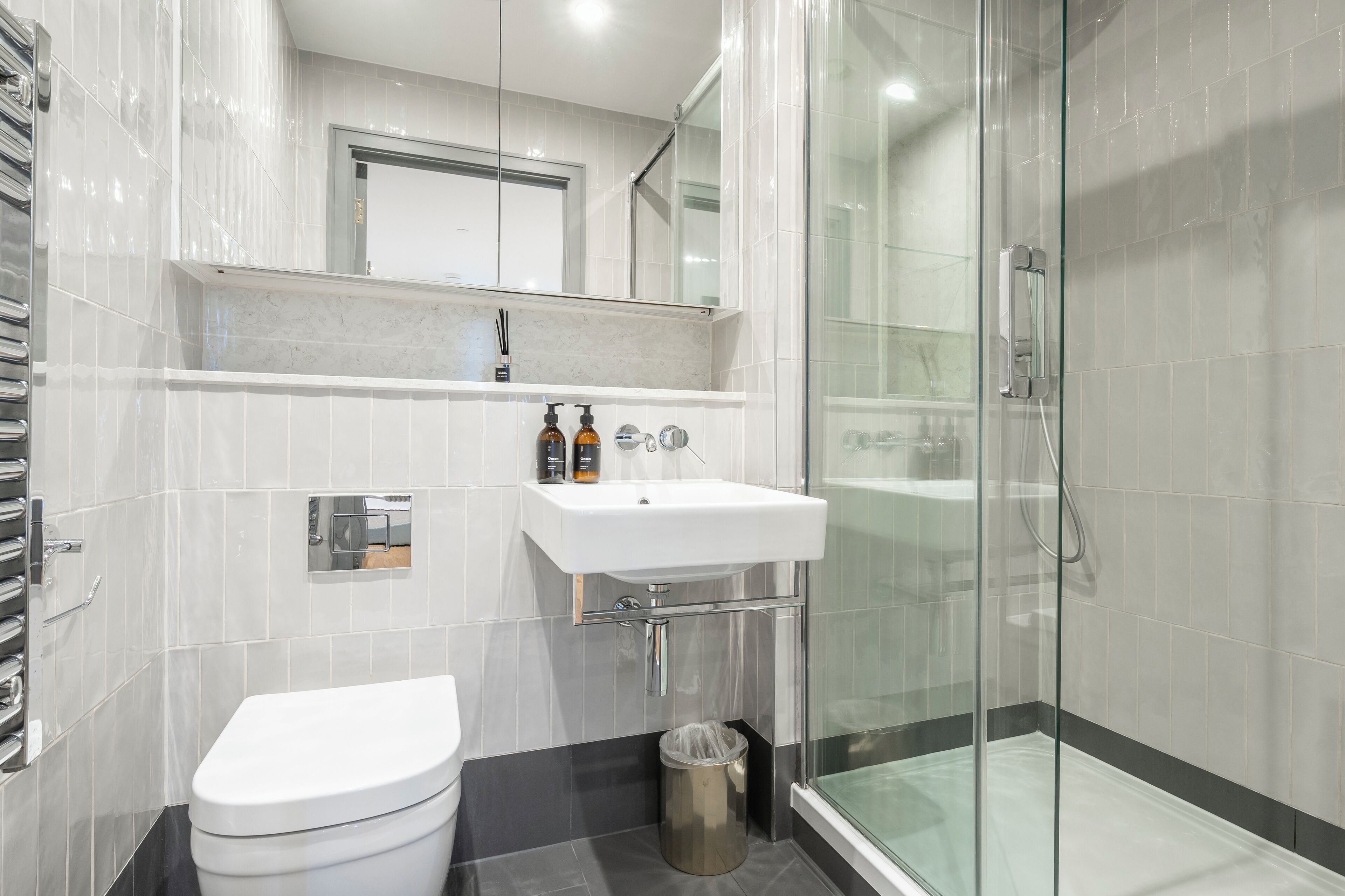 A modern bathroom with a glass shower enclosure, a white sink, and a toilet.