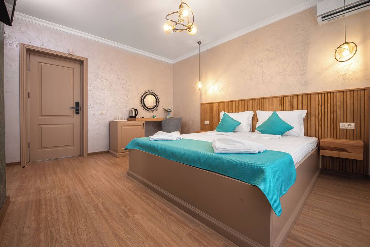 Un dormitorio con una cama, mesitas de noche, un espejo y un cabecero de madera.