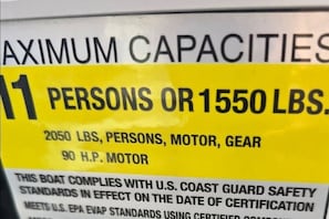 A label indicating maximum capacities for a boat, including 11 persons or 1550 lbs, 2050 lbs total, motor, and gear, and 90 hp motor.