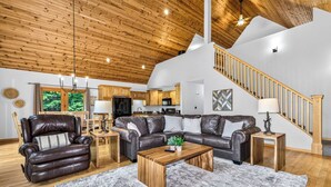 A spacious living room with a leather sofa, wooden coffee table, and a staircase leading to an upper level.