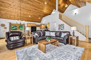 A spacious living room with a leather sofa, wooden coffee table, and a staircase leading to an upper level.