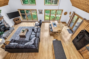 A spacious living area with a large sofa, dining table, and a fireplace. - Stepaway Vacation Rentals- Stay-A-While (Eagle River)
