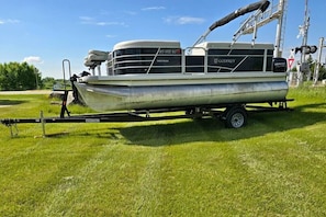 A boat trailer with a boat on it, parked on grass.
