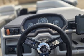 A vehicle's dashboard with a steering wheel, speedometer, and control panel.