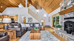 A spacious living area with a stone fireplace, a leather sofa, and a wooden coffee table.