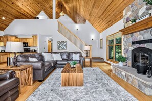 A spacious living area with a stone fireplace, a leather sofa, and a wooden coffee table.