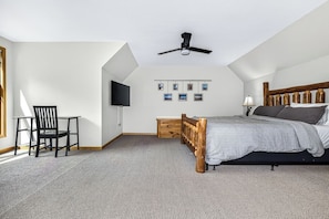 A bedroom with a bed, a chair, a television, and a ceiling fan. - Stepaway Vacation Rentals- Stay-A-While (Eagle River)