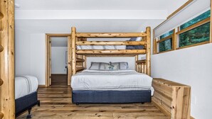 A bedroom with a bunk bed, a wooden headboard, and a window with a view of trees.