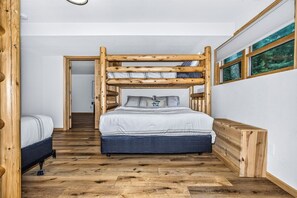 A bedroom with a bunk bed, a wooden headboard, and a window with a view of trees.