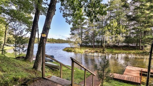 A lakeside deck with wooden railings and a small staircase leading down to the water.