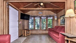 A cabin with a wooden interior, a red sofa, a television, and a ceiling fan.