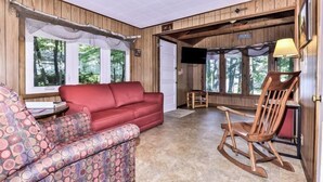 A cozy room with a red sofa, patterned armchair, and wooden rocking chair.