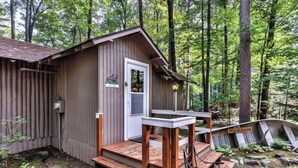 A rustic cabin with a wooden deck and a small porch.
