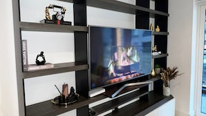 A modern living room with a flat-screen TV mounted on a black and white shelving unit.