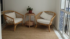 A room with two wicker chairs, a small table with a potted plant, and a patterned floor runner. - Charming cottage in a quiet environment (Nerja)