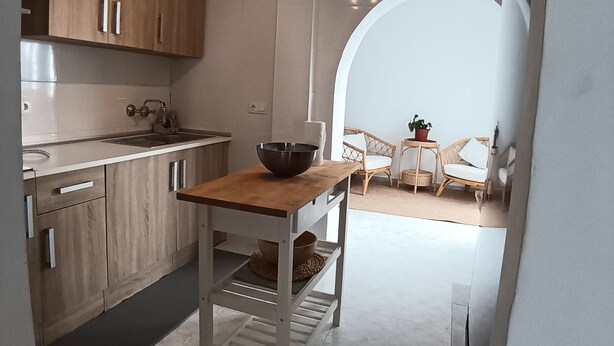 A modern kitchen with wooden cabinets, a white countertop, and a bowl on a table. - Charming cottage in a quiet environment (Nerja)