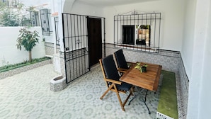 A covered patio area with a wooden table and chairs, a small potted plant, and a decorative metal gate. - Charming cottage in a quiet environment (Nerja)