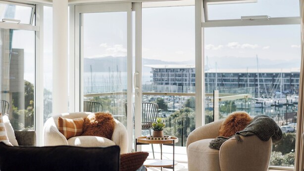 A modern living room with a large glass door leading to a balcony with a marina view.
