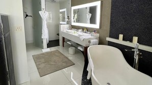 A modern bathroom with a freestanding bathtub, a large mirror, and a vanity with a sink and mirror. - Studio suite in Luxurious resort with scenic view in amazing Cabo San Lucas  (Cabo San Lucas)