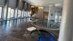 A modern indoor swimming pool with a glass wall, a central hot tub, and a tiled floor. - Studio suite in Luxurious resort with scenic view in amazing Cabo San Lucas  (Cabo San Lucas)