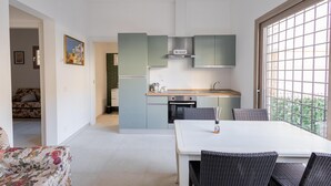 Una cocina moderna con gabinetes verde claro, una mesa de comedor blanca y sillas de mimbre.