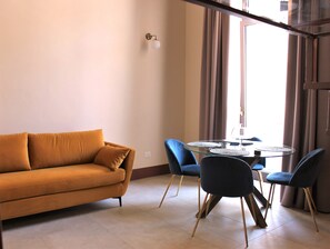 A modern living room with a sofa, a glass-top dining table, and chairs. - Palazzo sul Corso - Elegant frescoed loft in the center of Brindisi (Brindisi)