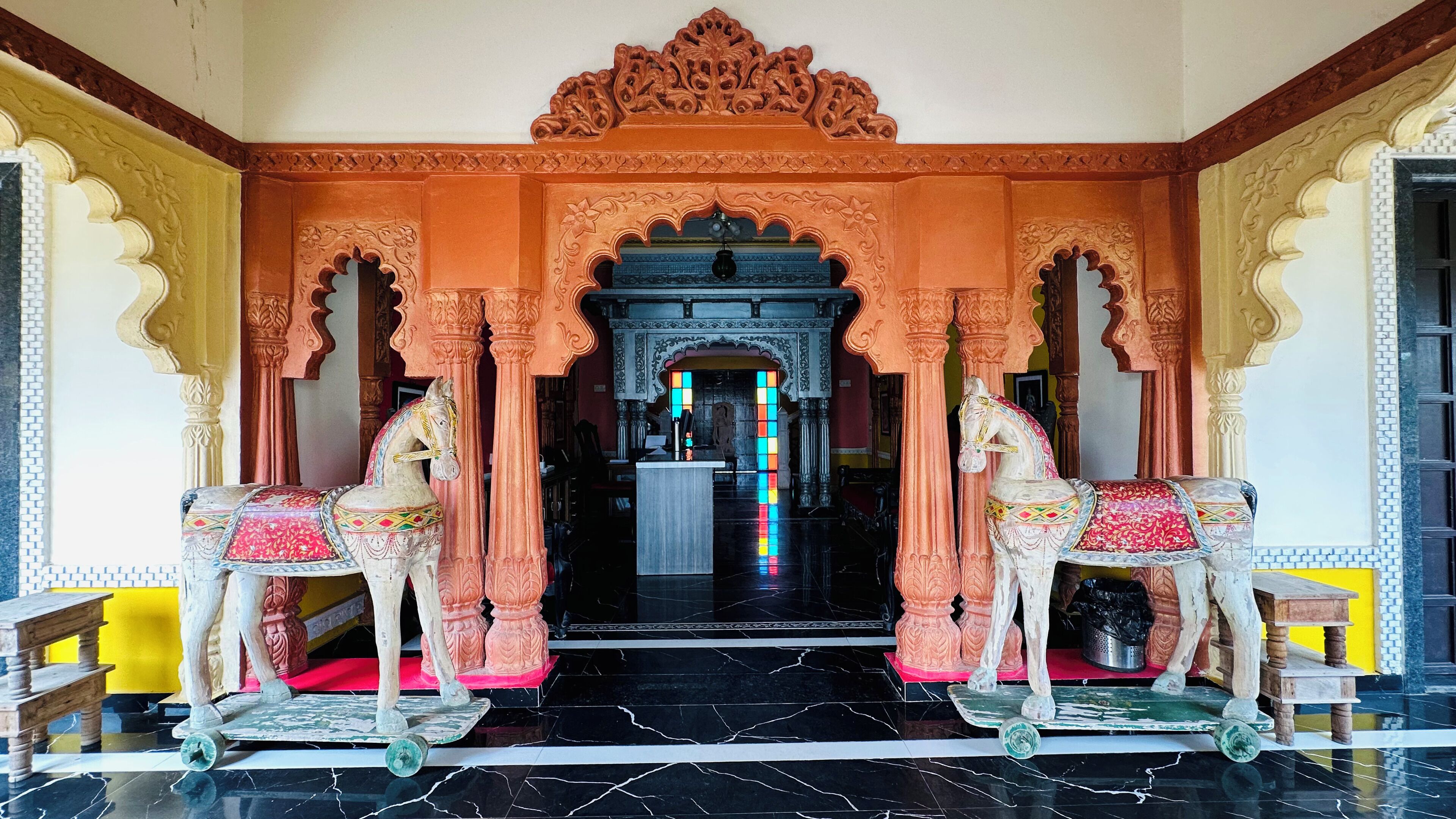 An ornate entrance with two horse statues, a tiled floor, and a central doorway.