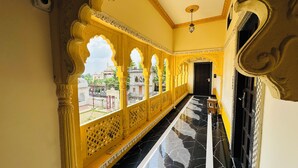 A corridor with ornate yellow arches and a black marble floor, leading to a dark door. - Rajgadhh Palace Resort (Palanpur)