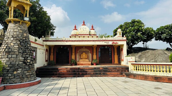 A temple with a stone pillar, a central statue, and a tiled entrance area.