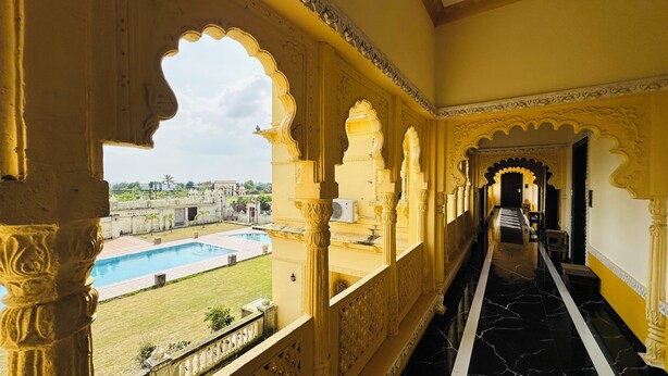 A corridor with ornate arches and a view of a swimming pool. - Rajgadhh Palace Resort (Palanpur)