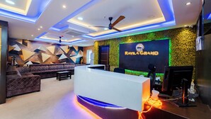 A modern reception area with a reception desk, sofas, and a ceiling fan. - Ravila Grand Hotel (Hyderabad)