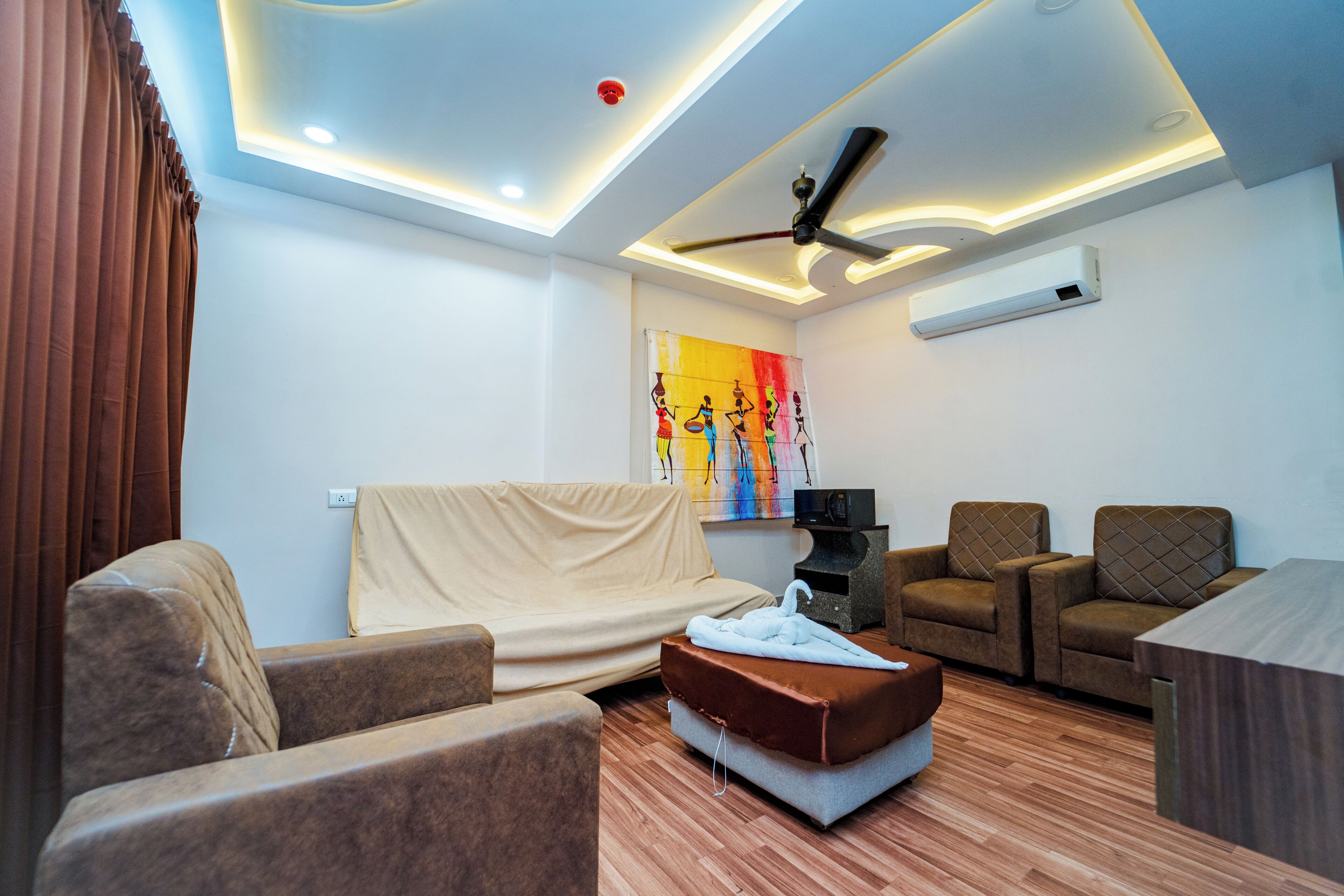 Un salon moderne doté d’un ventilateur de plafond, d’un canapé, d’une causeuse, d’une table basse et d’un appareil de climatisation.