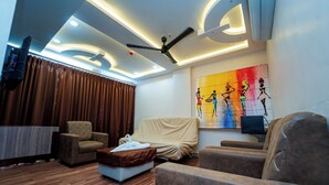 A modern room with a ceiling fan, a painting, and a covered sofa. - Ravila Grand Hotel (Hyderabad)