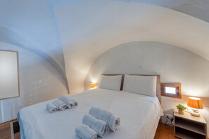 A bedroom with a curved ceiling, a bed with white linens, two bedside lamps, and a small window. - Apartment 'Ecce35 Stay' with Wi-Fi and Air Conditioning (Lecce)