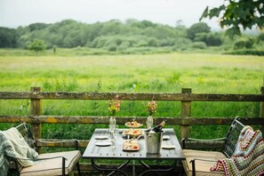 An outdoor dining setup with a table, chairs, and a metal bucket with a bottle. - Country Dual Cottage Stay | Comfortably Sleeps 6 (Pembrokeshire)