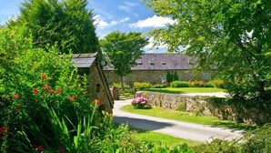 A rural setting with a stone building, a winding road, and lush greenery.