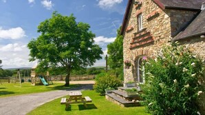 A stone building with a picnic table and a playground in the background.