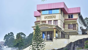 A multi-story building with a prominent entrance and a balcony. - RAJA STONE PALACE (Kodaikanal)