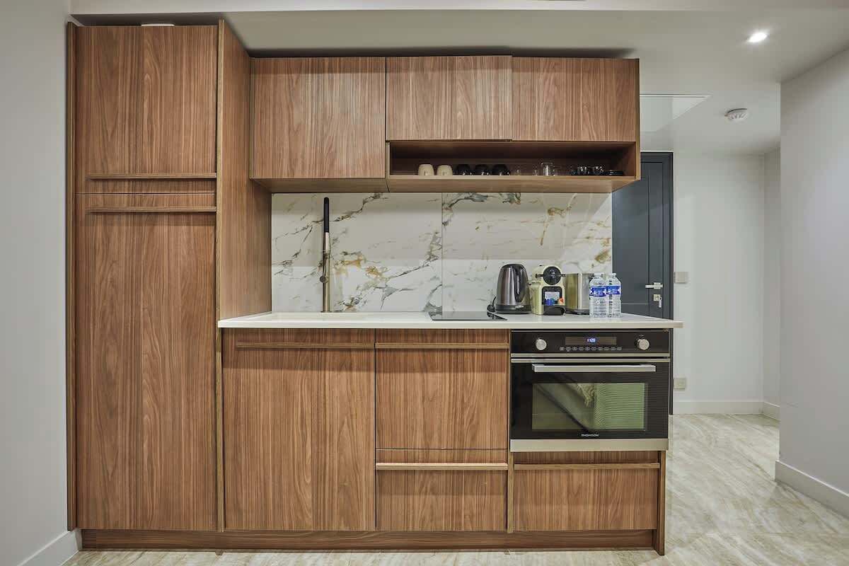 Een compacte keuken met houten kastjes, een marmeren achterwand en een ingebouwde oven.
