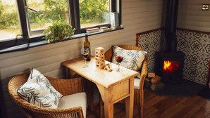Un rincón acogedor con una mesa de madera, sillas de mimbre, una chimenea y una ventana con vistas al verdor.