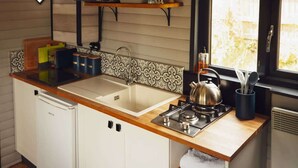 Cocina compacta con pileta, estufa y microondas. Hay placares, una ventana con vista y una repisa con utensilios de cocina.