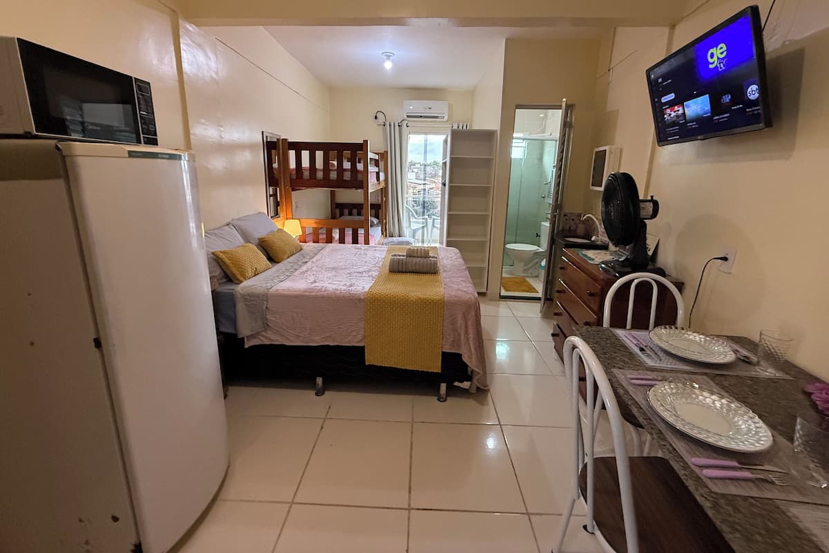 A compact hotel room with a bed, a desk, a TV, and a refrigerator.