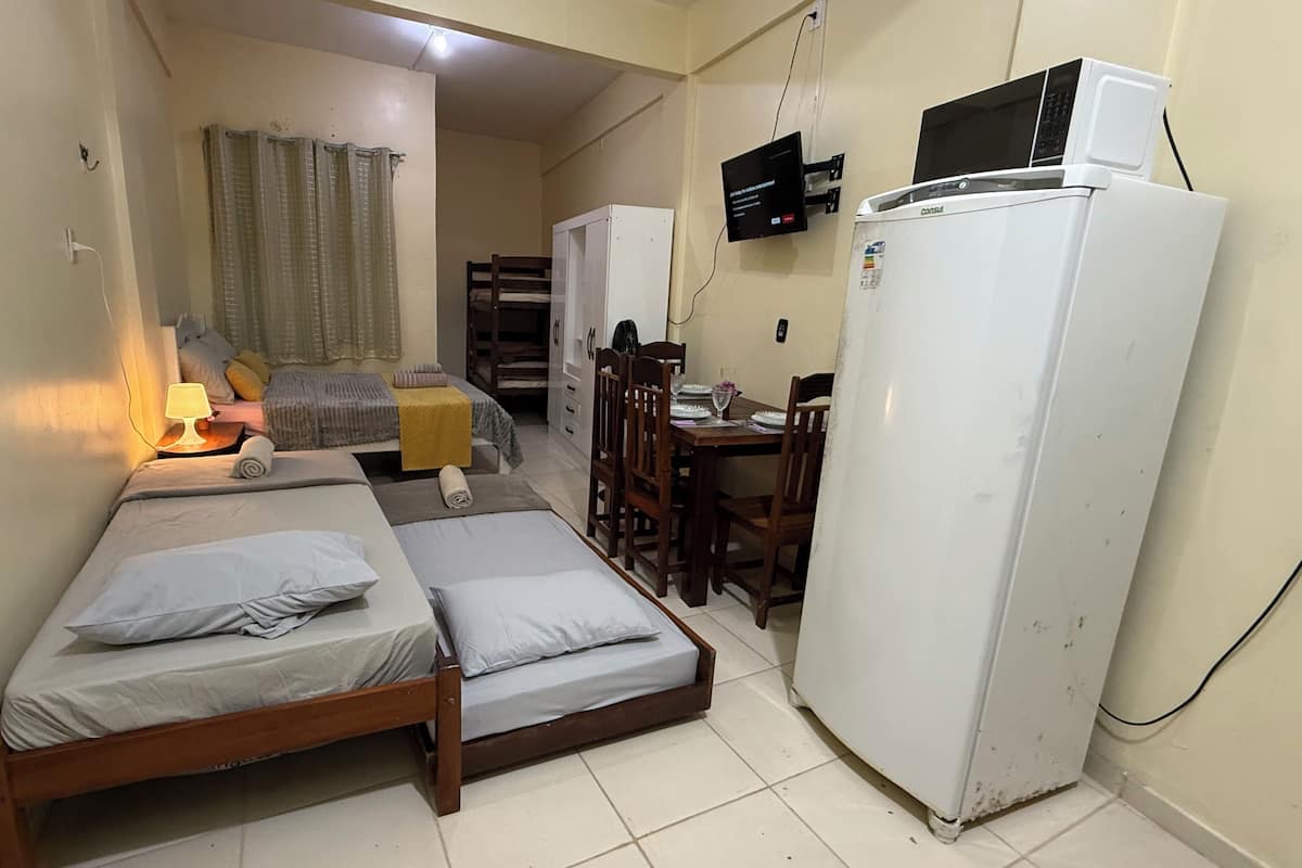 A compact room with two beds, a dining table, a refrigerator, and a television.